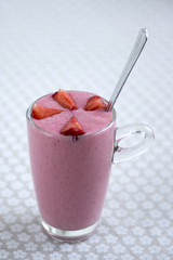 Fresh milk and strawberries drink in the glass on floral pattern tablecloth, tasty and healthy fruit milkshake