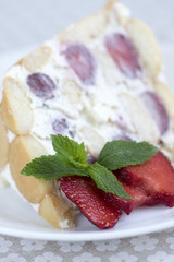 Fresh cream cake with fresh strawberries and rounded ladyfingers on the plate with fresh red fruits