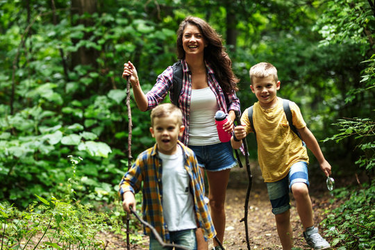 Mother and her little sons hiking trough forest .They learning about nature.