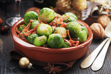 Brussels sprouts with bacon, and caramelised onion on a black rustic table.