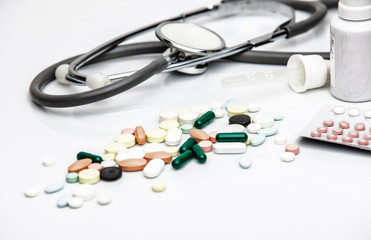 Pills, syringe and phonendoscope against white background