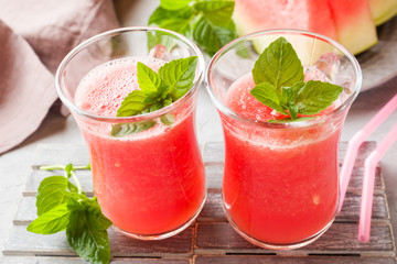 Fresh watermelon smoothie with ice and mint leaves in glasses.