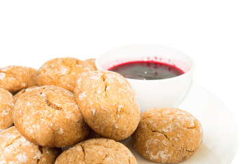 Sweet cakes on white plate and saucer with berry jam at isolated white background