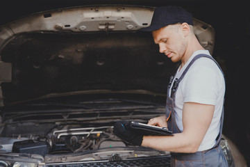 Professional car mechanic using electrnoic diagnostic equipment laptop in auto repair service.