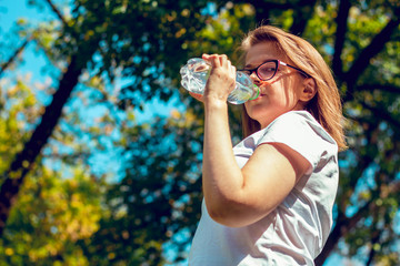 Girl looking in the camera while drinking water from a bottle