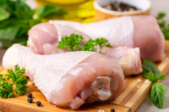 Raw chicken legs with spices and herbs on cutting board