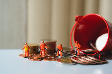 Miniature people, technician working on stack coins using as business and industry concept