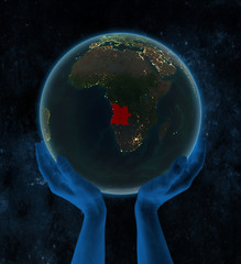 Angola on night Earth in hands in space