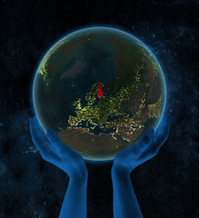 Finland on night Earth in hands in space