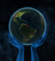 Guyana on night Earth in hands in space