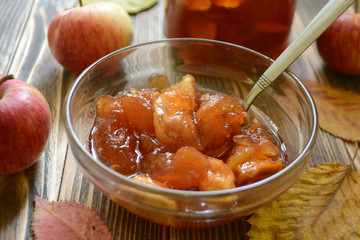 Homemade apple jam in transparent plate on wooden background