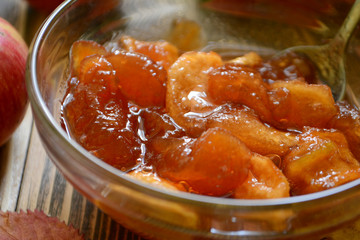 Apple jam in transparent plate on wooden background