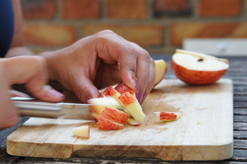 frau schneidet apfel mit messer in hand