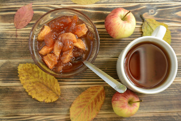 Cup of tea, Apple jam in transparent plate on wooden background
