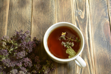 Obraz na płótnie Canvas Cup of tea and oregano on a wooden background herbal tea
