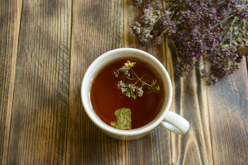 Cup of tea and oregano on a wooden background herbal tea