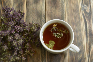Cup of tea and oregano on a wooden background herbal tea
