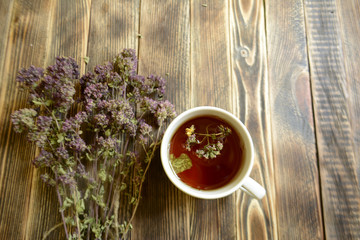 Cup of tea and oregano on a wooden background herbal tea