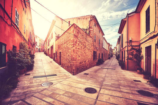 Vintage stylized picture of a street corner in Alcudia old town at sunset, Mallorca, Spain.