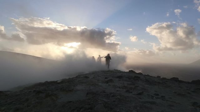 Hikers at sunset on the crater of Vulcano with sulfur fumaroles, Aeolian Islands