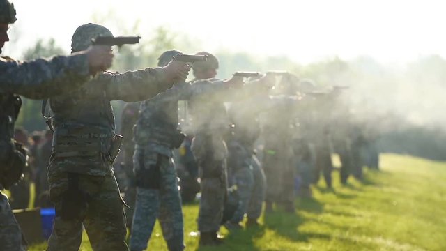 Army soldiers fire pistols and handguns at a firing range.