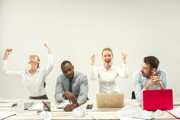 Winners. Young african and caucasian men and women sitting at office and working on laptops. The...