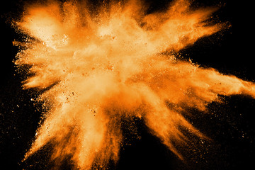 Abstract explosion of orange dust on white background. Freeze motion of orange dust splashing.