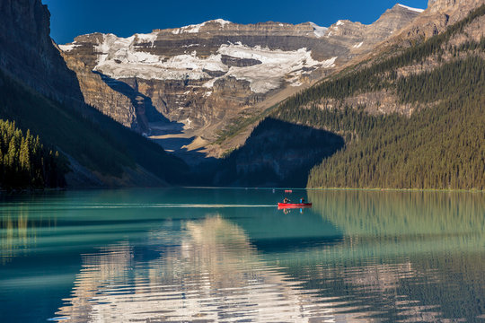 Banff, Canada - Ago 19th 2017 - Tourists doing kayak and enjoying the amazing scenario of lake Moraine, early morning light, glacial at the background, blue sky in summer time Banff.