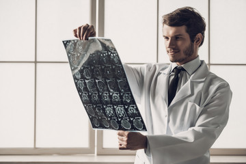 Young Smiling Doctor Looking at MRI Scan of Brain