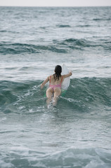 Young woman surfing the wave on his surfboard