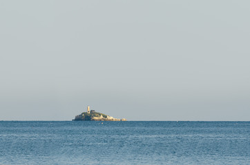 Tropical island on open sea with light tower