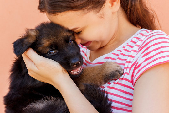 Young woman enjoys hugging a small cute puppy