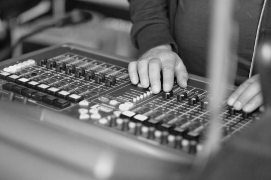 Hands of the sound engineer on the mixing console during the concert