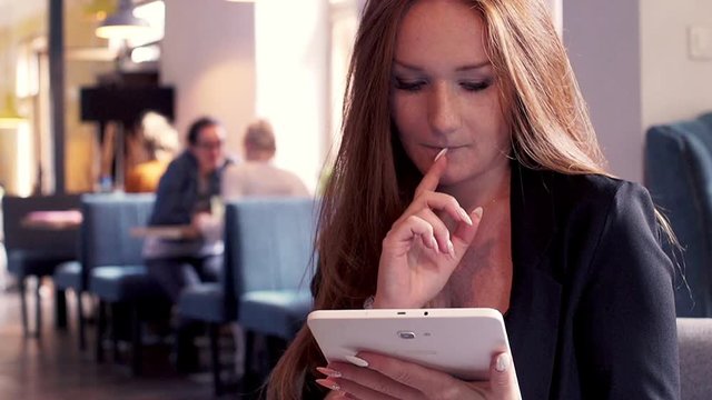 Young beautiful businesswoman sitting withn tablet in cafe

