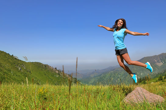 Happy young woman jumping against mountains