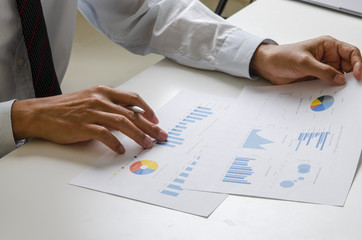 Businessman analyzing printed financial charts and graphs on desk showcasing corporate data review...