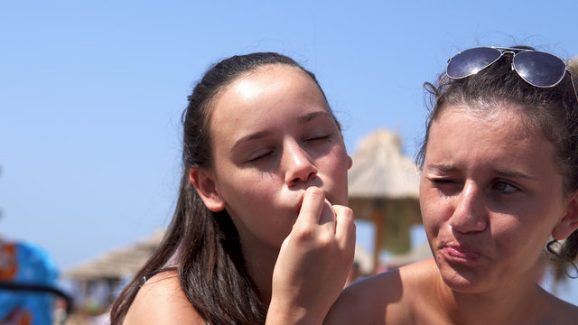 Young beautiful girls refresh on beach eating grapes and kissing at summertime, cinematic dof