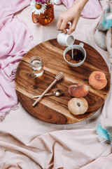 Cozy autumn or winter flatlay of wooden tray with cup of coffee, peaches, creamer with plant milk,...