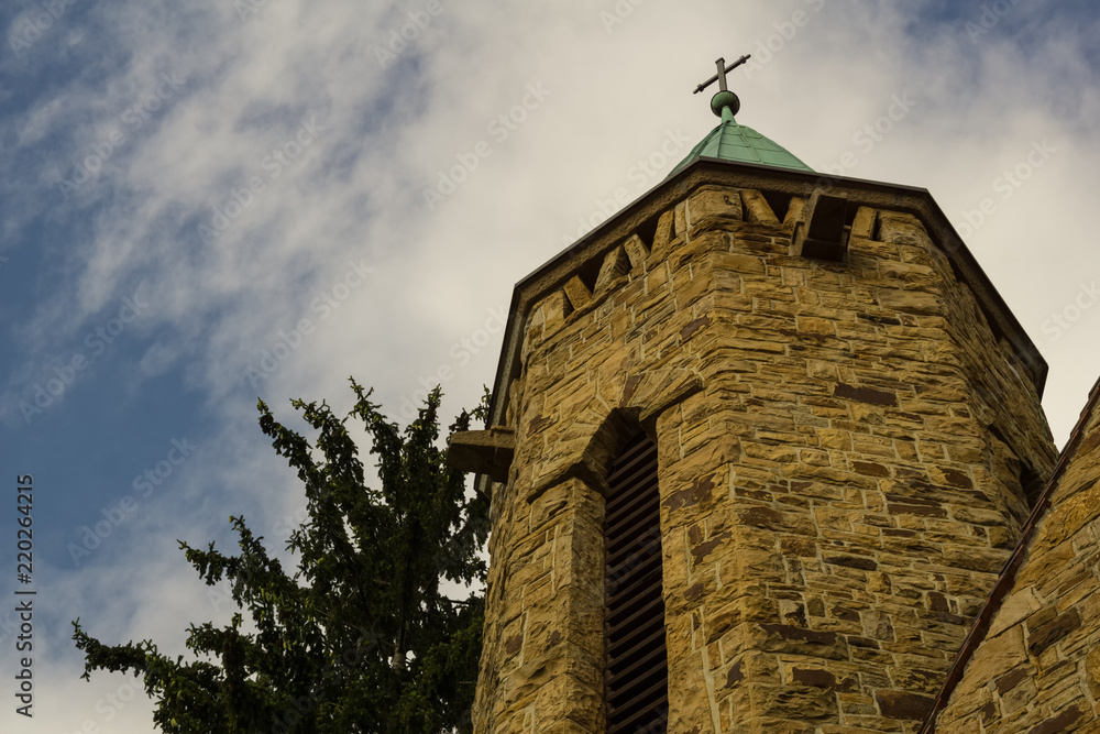 Wall mural an old church tower below a cloudy summer sky