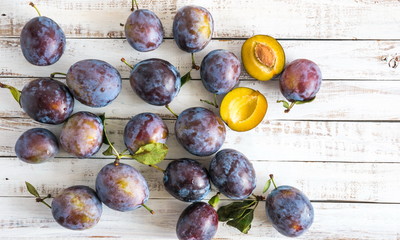 Plums on a white rustic wooden background. Juicy fresh blue plums close-up. Flat lay, top view,...