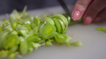 Chopping Leeks on a wooden board focus on sliced leeks