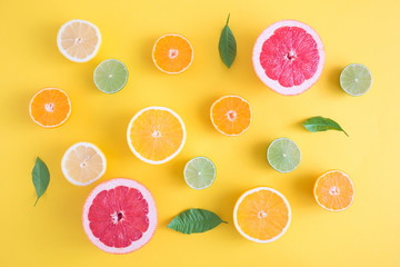 Creative background made of summer tropical fruits with leaves, grapefruit, orange, tangerine, lemon, lime on pastel yellow background. Food concept. Flat lay, top view, copy space 