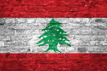 Flag of Lebanon over an old brick wall background, surface