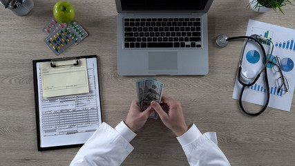 Top view of medical worker counting many dollar bills, expensive healthcare