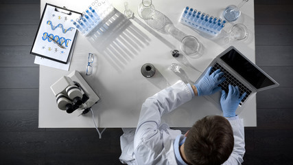Chemist writing down results of chemical experiments on computer, top view © motortion