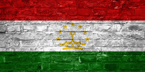 Flag of Tajikistan over an old brick wall background, surface