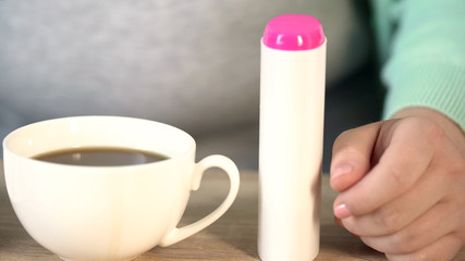 Tea and sweetener, plump woman sitting at table, diabetes concept, closeup