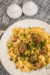 Tagliatelle pasta with pork meatballs and dill sauce. Selective focus.