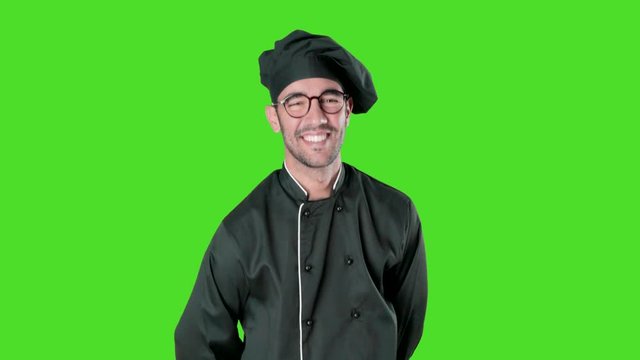 Happy young chef posing against green background