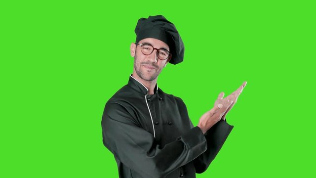 Concept of a young chef inviting you to his restaurant with a gesture of welcome against green background
